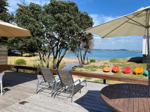 a patio with chairs and a table and an umbrella at Bay of Islands Beachfront - Tapeka del Mar in Russell