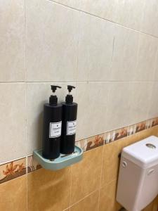 duas garrafas pretas numa prateleira ao lado de uma sanita em Mutiara Chalet Bandar Melaka em Malaca