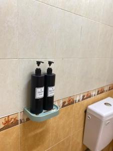 two black bottles on a shelf next to a toilet at Mutiara Chalet Bandar Melaka in Melaka