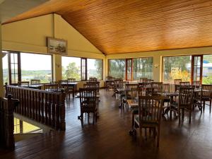 a dining room with tables and chairs and windows at Tea Bush Hotel in Nuwara Eliya