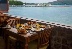 stół z talerzami jedzenia obok wody w obiekcie Colibri Hotel w mieście Baie Sainte Anne