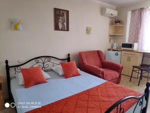1 dormitorio con 1 cama con almohadas de color naranja y silla en Villa Blues Guest House, en Koktebel