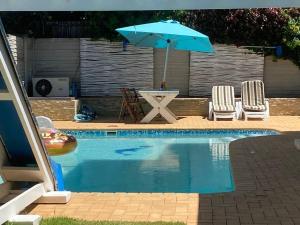 uma piscina com uma mesa e um guarda-sol e cadeiras em 53 @ Constance em Mount Pleasant