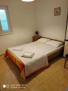Schlafzimmer mit einem Bett mit weißer Bettwäsche und einem Fenster in der Unterkunft Apartment ZAGLAV 1 in Zaglav