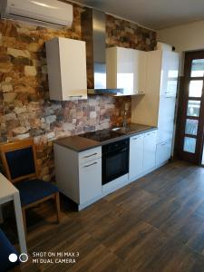 a kitchen with white cabinets and a stone wall at Apartment ZAGLAV 1 in Zaglav