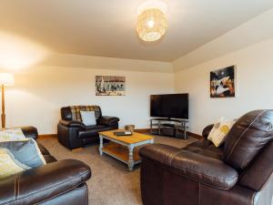 a living room with leather furniture and a flat screen tv at The Middle Byre in Girthon