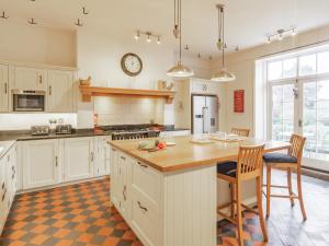 uma cozinha com armários brancos, uma mesa e um relógio em The Lodge em Snainton