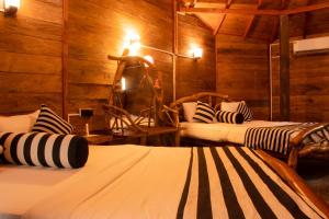 two beds in a room with wooden walls at Dudley Nature Resort in Habarana