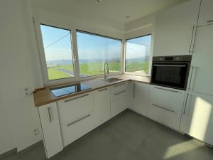 eine Küche mit weißen Schränken und einem großen Fenster in der Unterkunft Penthouse mit Ausblick in Bad Schwalbach