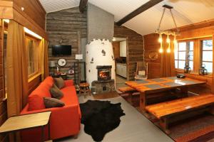 a living room with a red couch and a table at Kuukkeli Log Houses Aurora Cabin - Jaspis in Saariselka