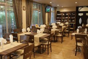 Un restaurante con mesas y sillas de madera y ventanas. en Hotel Zaara, en Sunny Beach