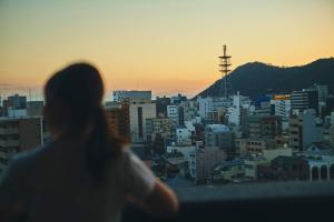 Une femme qui regarde la ville au coucher du soleil dans l'établissement FAV HOTEL TAKAMATSU, à Takamatsu