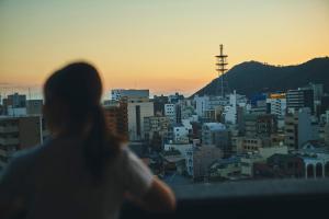 uma mulher a olhar para a cidade ao pôr-do-sol em FAV HOTEL TAKAMATSU em Takamatsu