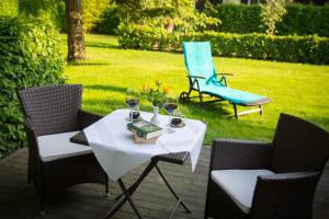 a table and chairs with wine glasses and a bench at Hotel & Restaurant Waldschlösschen in Kyritz