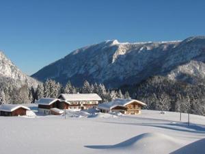 eine Gruppe von Gebäuden im Schnee mit Bergen in der Unterkunft Gästehaus Marchler in Bischofswiesen
