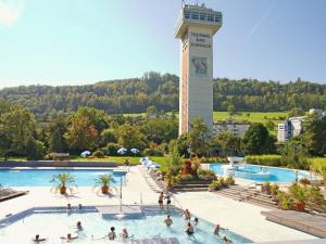 a group of people in a swimming pool with a tower at Hotel zur Post in Bad Zurzach