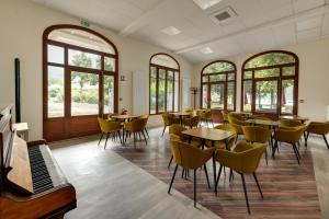 - une salle à manger avec des tables, des chaises et des fenêtres dans l'établissement Le Pavillon des Fleurs, à Menthon-Saint-Bernard