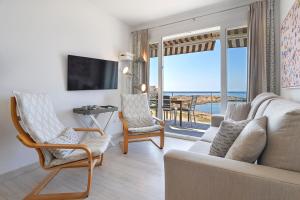 ein Wohnzimmer mit einem Sofa und Stühlen sowie Meerblick in der Unterkunft APARTMENT SES BAULES in Colonia Sant Jordi