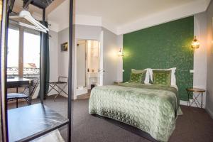 a bedroom with a bed with a green wall at Hôtel Azur in Reims