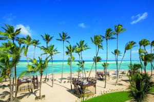 a beach with palm trees and tables and the ocean at Breathless Punta Cana Resort & Spa - Adults Only in Punta Cana