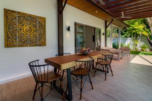 a dining room with a wooden table and chairs at villa Akala in Ban Saiyuan (1)