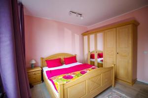 a bedroom with a large bed with pink sheets and red pillows at Serviced Apartement Xanthurus in Schwelm