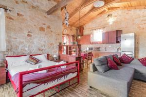 a bedroom with a bed and a couch and a kitchen at Casa Petra - Stone Cottage Farmhouses in Argasi