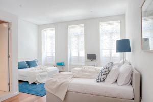 a white living room with a white couch and windows at Charming House Marquês in Porto