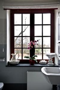 a bathroom with a window with flowers on a counter at Rezydencja Dwór Polski in Bełchatów