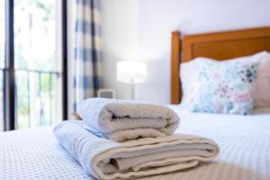 a pile of towels sitting on top of a bed at Praia da Luz Monique Apartment in Luz