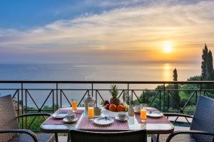 a table with a bowl of fruit on a balcony with the sunset at Xigia Escape villas in Khartáta