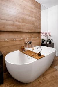 a large white tub in a bathroom with wooden walls at EXCLUSIVE EuApartments in Grodno