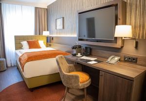 a hotel room with a bed and a desk with a television at Hotel Essener Hof; Sure Hotel Collection by Best Western in Essen