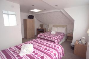 ブラックプールにあるMorrisy Houseのピンクと白のシーツが備わるベッド2台が備わるホテルルームです。