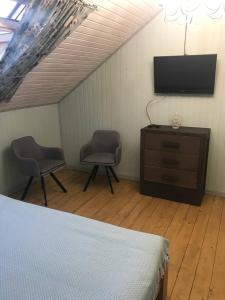1 dormitorio con 1 cama, 2 sillas y TV en Chalet Blanc, en Bukovel