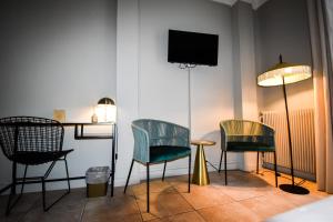 a room with two chairs and a tv on a wall at Hôtel Azur in Reims