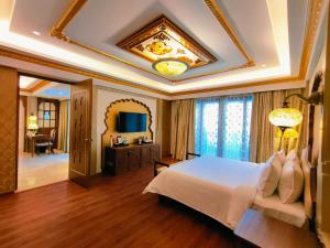 een grote slaapkamer met een bed en een televisie bij Kaldan Samudhra Palace in Mahabalipuram