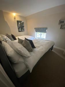 een slaapkamer met een bed met witte lakens en kussens bij The Cottage in Sulgrave