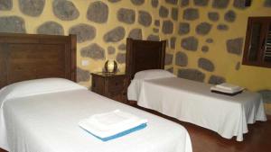 two beds in a room with rocks on the wall at El Rincon del Nublo in Tejeda