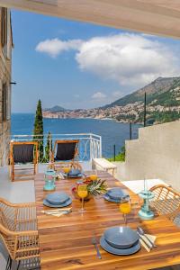 a wooden table with blue plates on it with a view of the ocean at St Jakov Superior Beach Apartment with Free Parking in Dubrovnik
