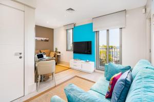a living room with a blue couch and a desk at Kronos on the Beach suite 3 in Barcelona