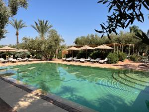 a large swimming pool with chairs and umbrellas at CASA ABRACADABRA in Marrakesh