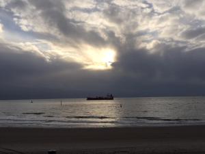 a boat in the ocean under a cloudy sky at Studio aan Zee in Westkapelle