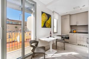 Kronos on the beach Suite 4 في برشلونة: مطبخ وغرفة طعام مع طاولة وكراسي بيضاء