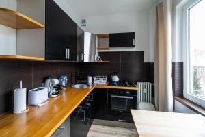 a kitchen with a wooden counter top and black cabinets at Apartament Moniuszki 22 in Toruń