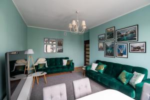 una sala de estar con paredes azules y sofás verdes en Apartament Moniuszki 22 en Toruń