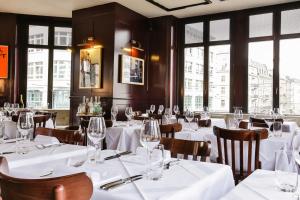 un restaurante con mesas y sillas blancas y ventanas en Boutique & Art Hotel Helvetia en Zúrich