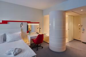 Cette chambre comprend un lit, une chaise rouge et un bureau. dans l'établissement Holiday Inn Vilnius, an IHG Hotel, à Vilnius