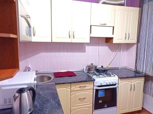 a kitchen with white cabinets and a stove and a sink at Уютные апартаменты c кондиционером на Уманчанке in Umanʼ