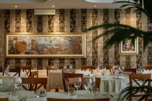 ein Restaurant mit Tischen und Stühlen und einem Gemälde an der Wand in der Unterkunft Hotel Mazzanti in Milano Marittima